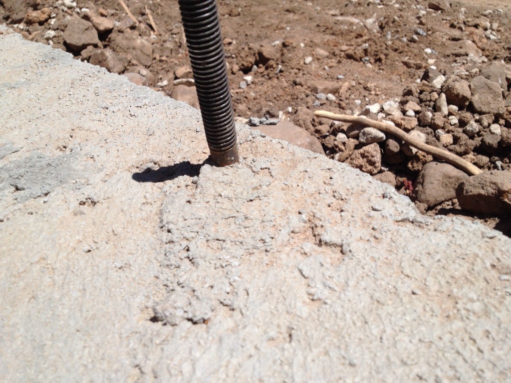 Foundation bolt in frost wall, with rough concrete surrounding it.